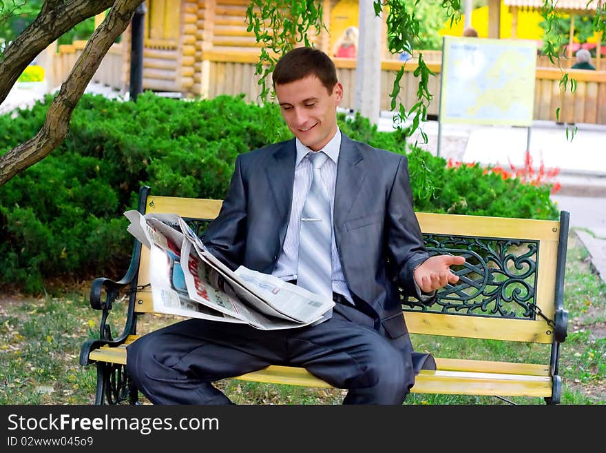 Young businessman reading a newspaper in the park