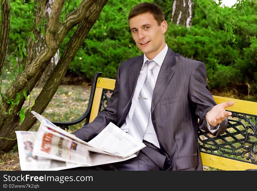 Young businessman reading a newspaper in the park