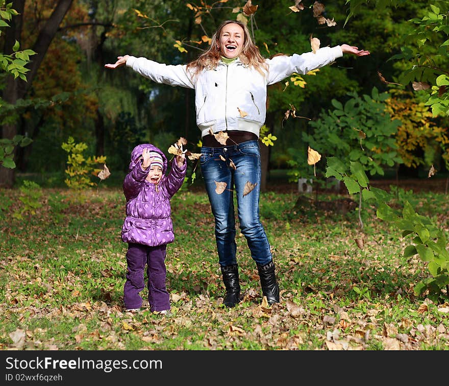 Mother and Daughter Throwing Dry Leaves in Autumn