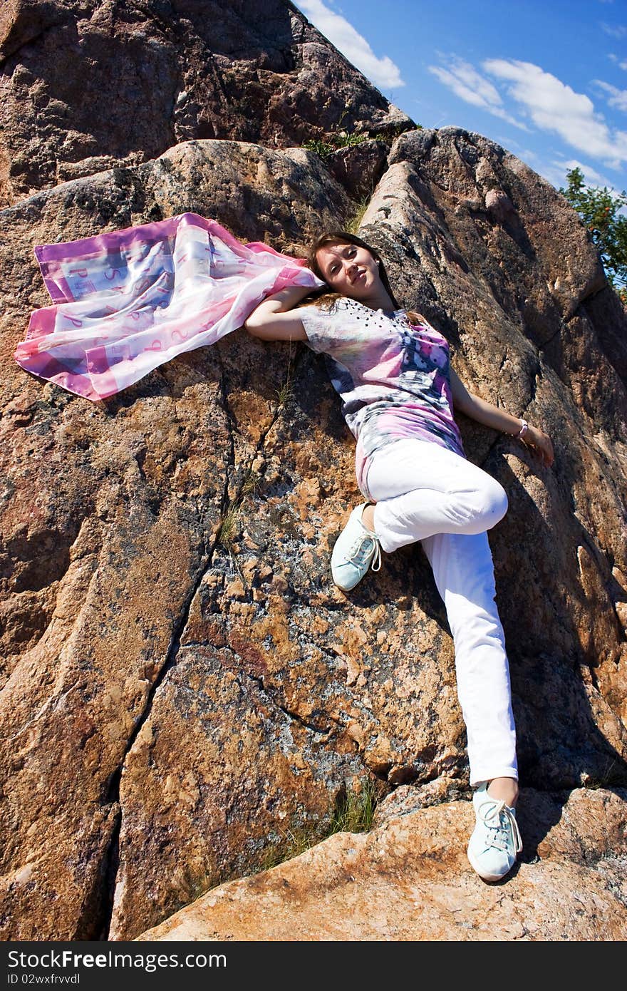 Positive young girl against the rock in summer