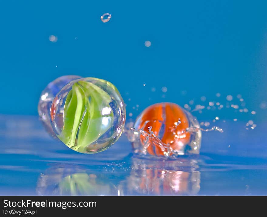 Marbles falling into blue water