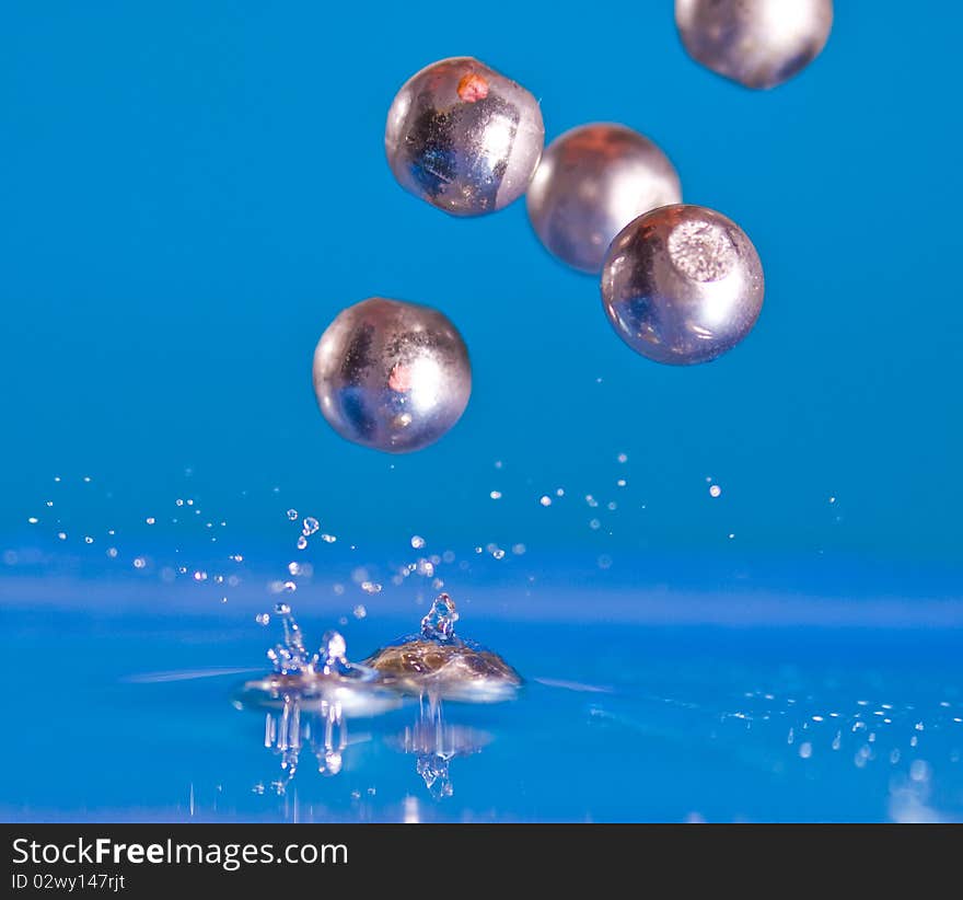 Marbles falling into blue water