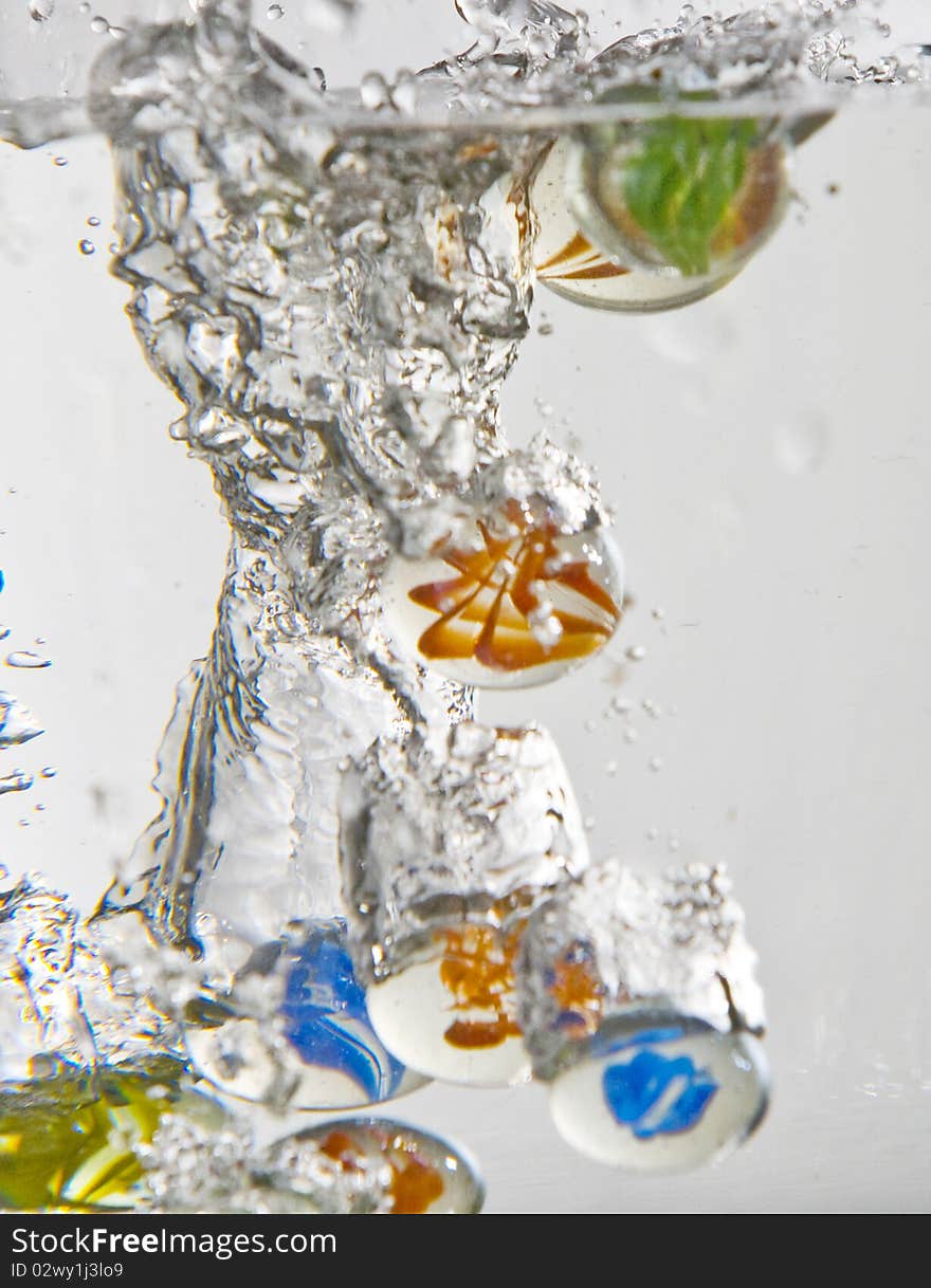 Marbles falling into water with white background. Marbles falling into water with white background