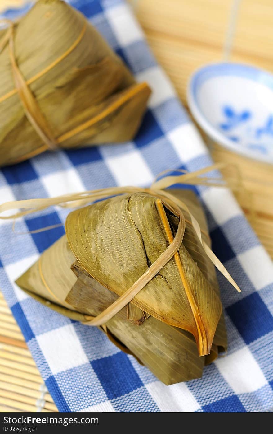 Two rice dumplings wrapped in traditional bamboo leaves.