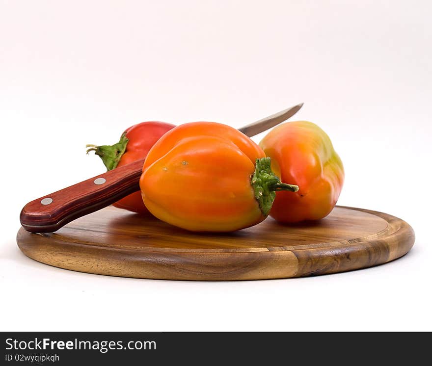 Colorful paprikas on wooden kitchen board isolated