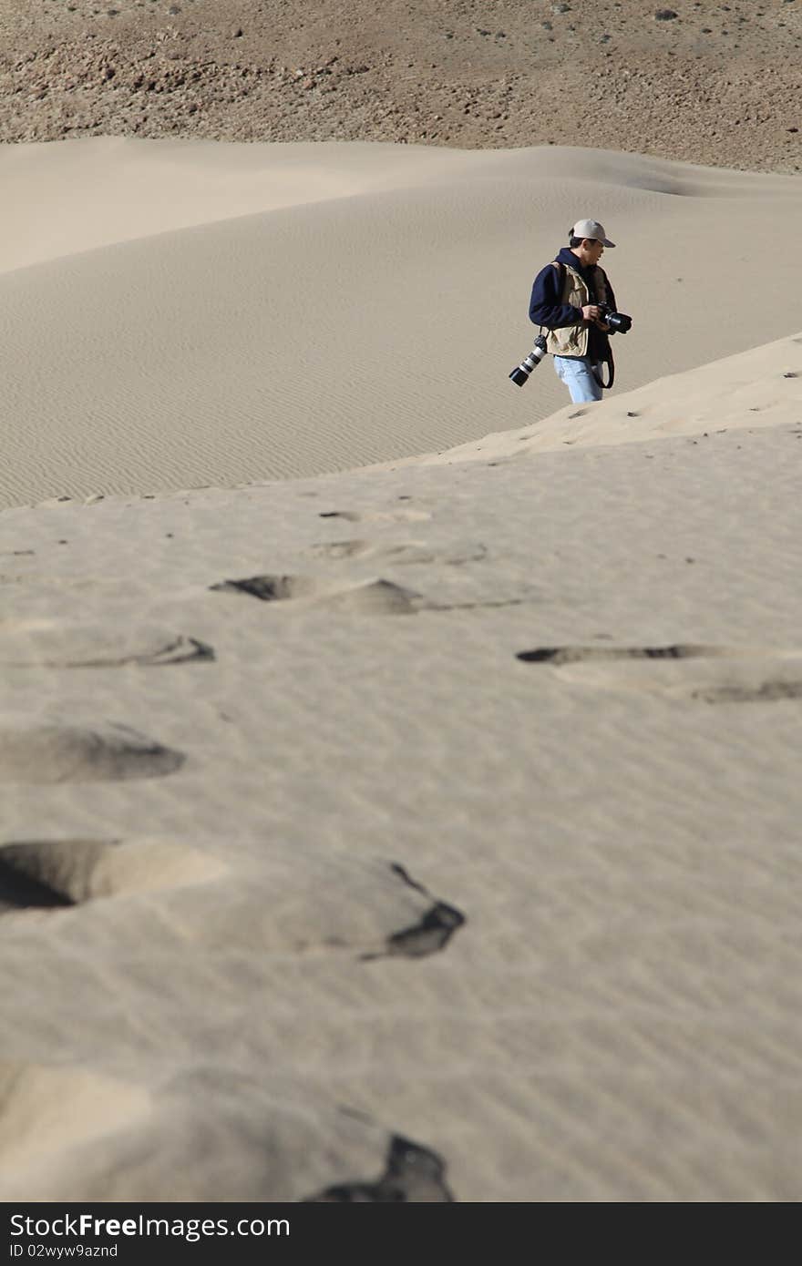 A photographer is walking in desert in Tibet, China. A photographer is walking in desert in Tibet, China