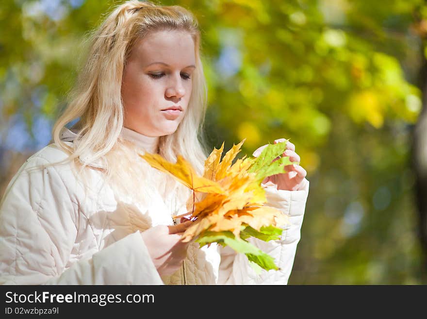 Girl looks at a bouquet of autumn leaves. Girl looks at a bouquet of autumn leaves