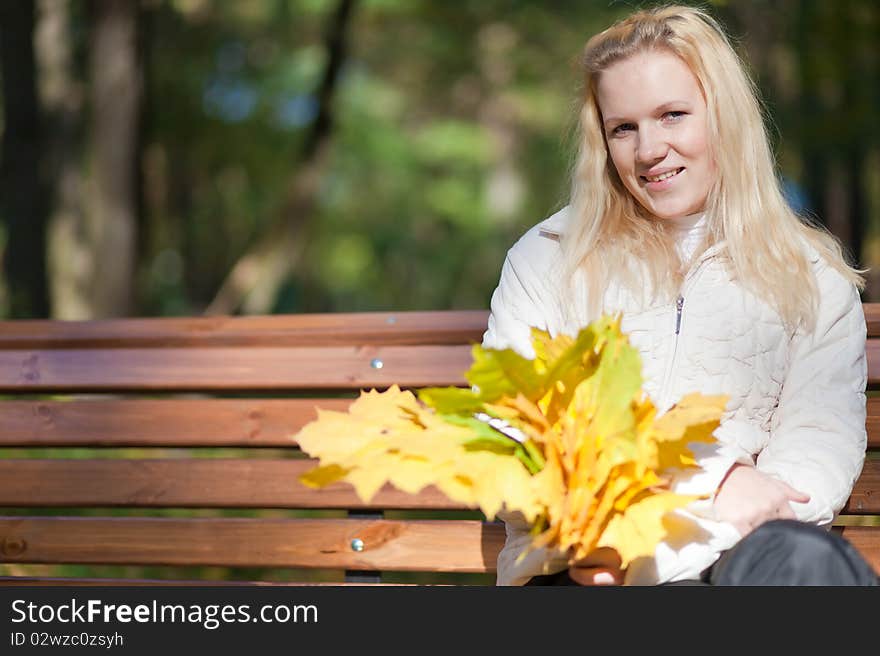 Girl sits on a bench and smiles autumn day