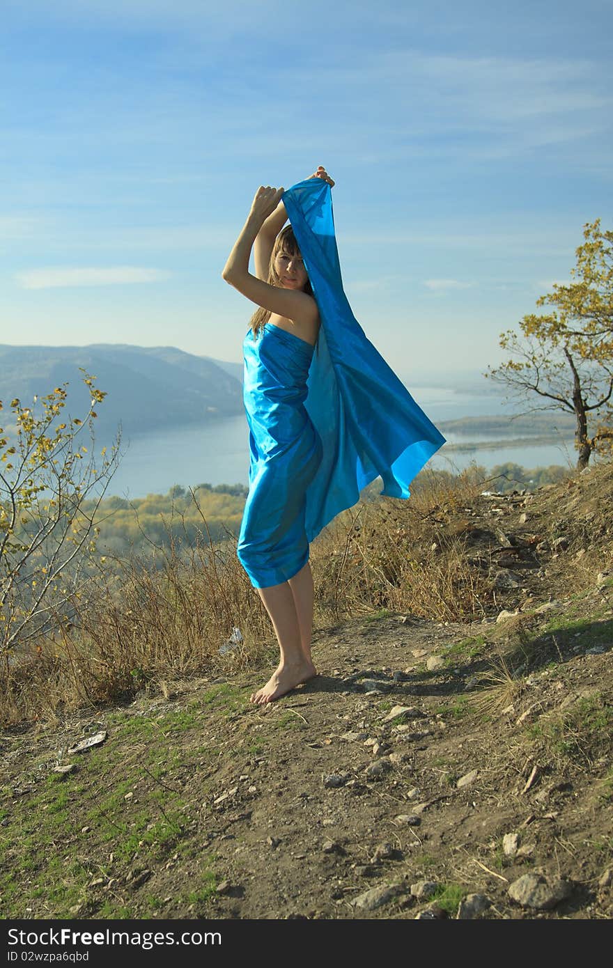 Young woman with blue fabric fluttering on wind . Young woman with blue fabric fluttering on wind .