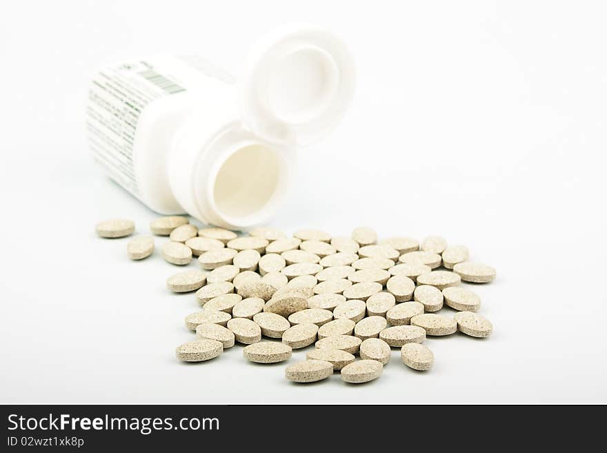 Heap of grassy tablets with a jar on a white background