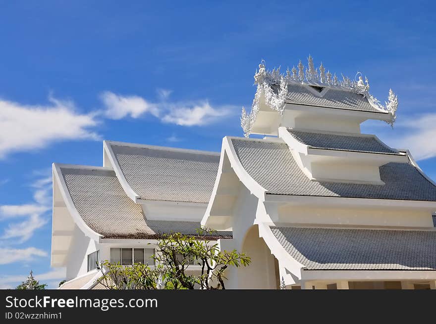 Roofs of Wat Rong Khun temple against blue sky