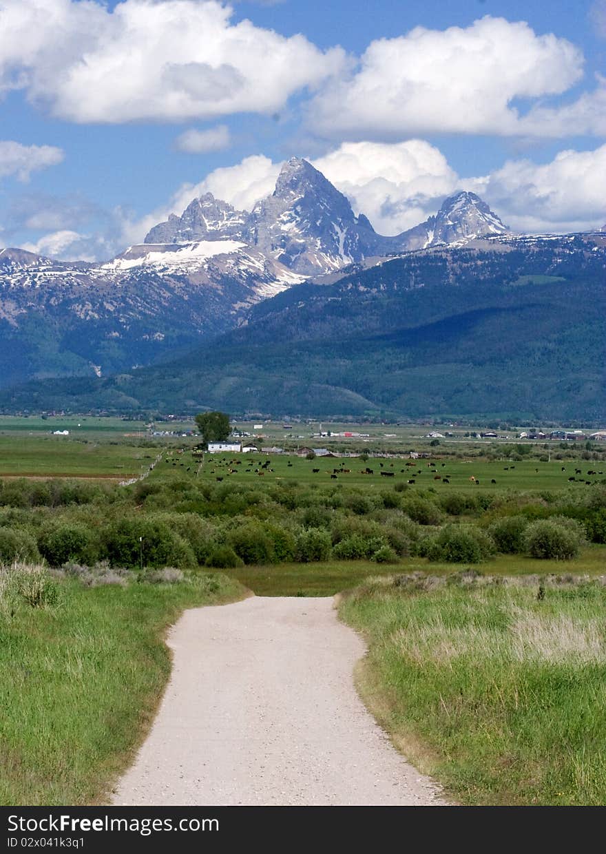 Dirt road leading to farmland at the base of the Teton mountains. Dirt road leading to farmland at the base of the Teton mountains