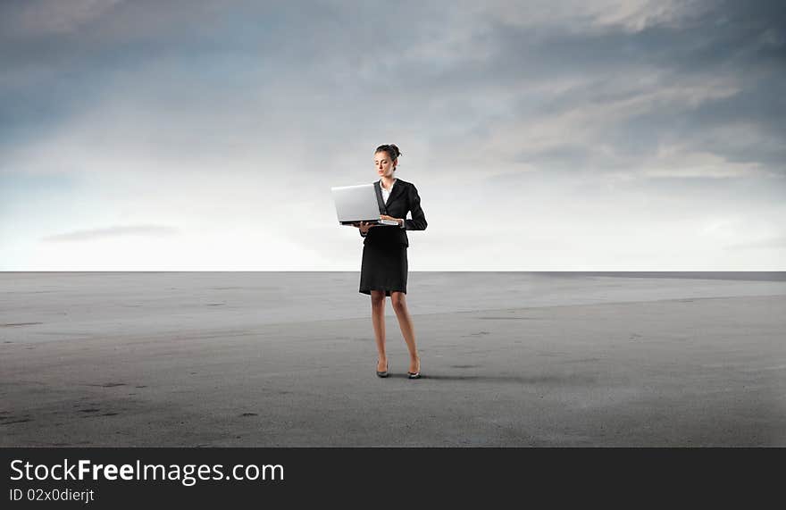 Businesswoman using a laptop in a desert. Businesswoman using a laptop in a desert