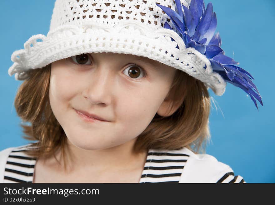 Portrait of the lovely girl in a white knitted cap. Blue background. Portrait of the lovely girl in a white knitted cap. Blue background.