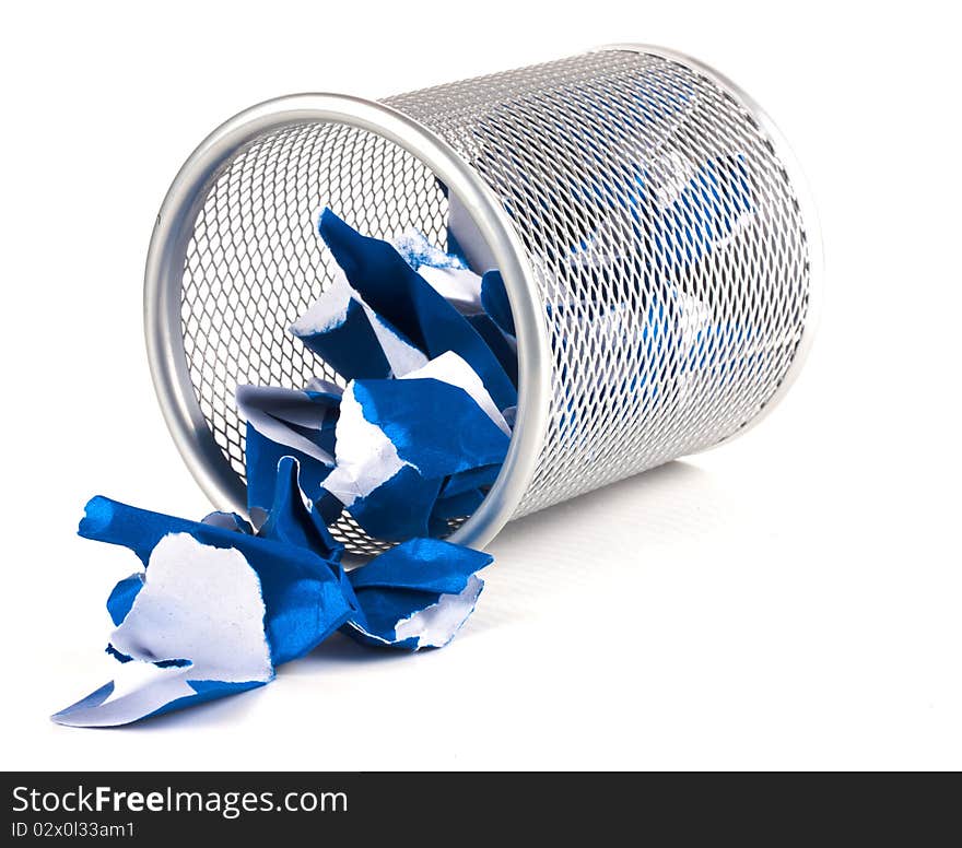 A silver mesh waste paper bin with blue paper spilling from it. A silver mesh waste paper bin with blue paper spilling from it