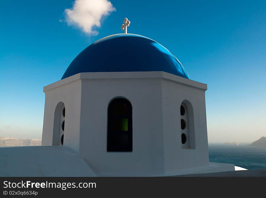 View on the sea and a typical greek church in the steep coast on top of the caldera in Santorini, Greece, all in the greek national colors white and blue. View on the sea and a typical greek church in the steep coast on top of the caldera in Santorini, Greece, all in the greek national colors white and blue.