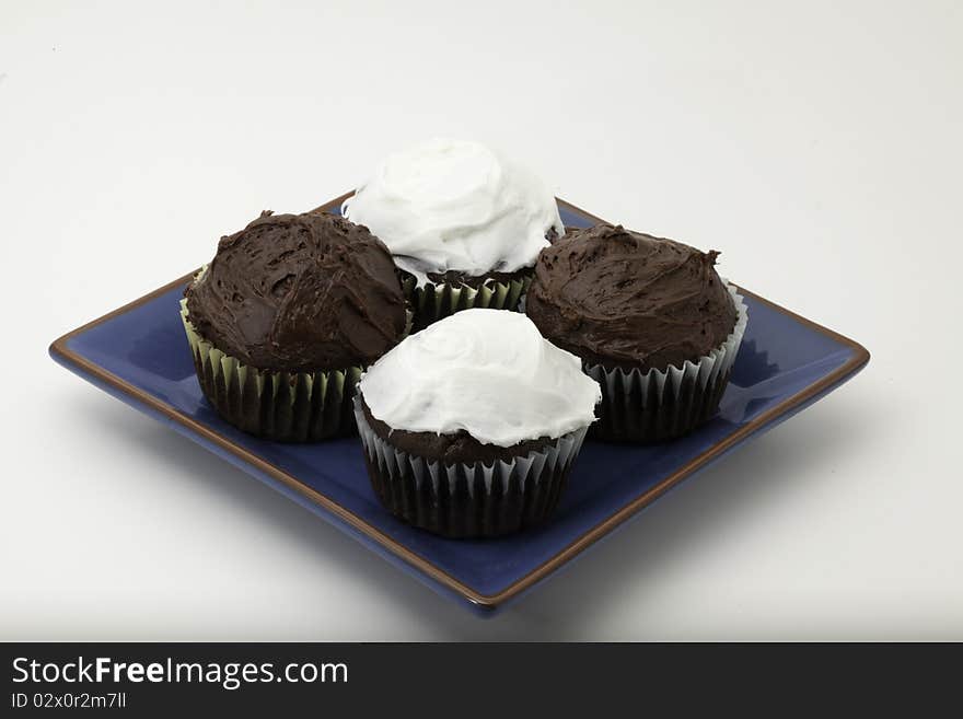 Chocolate cupcakes with chunks of chocolate on a plate with icing. Chocolate cupcakes with chunks of chocolate on a plate with icing.