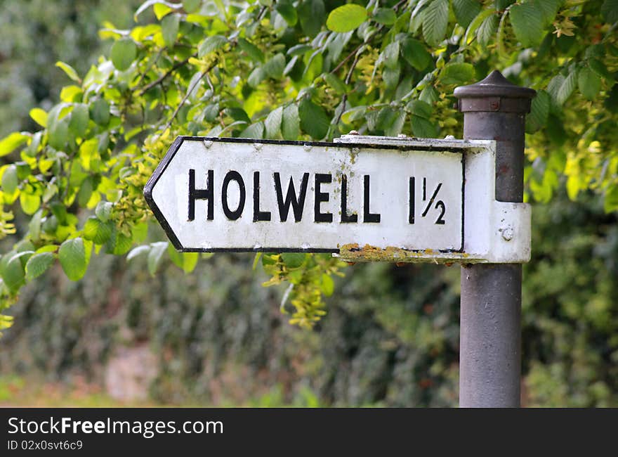 A sign post giving directions to Holwell with a hedge in the background. A sign post giving directions to Holwell with a hedge in the background