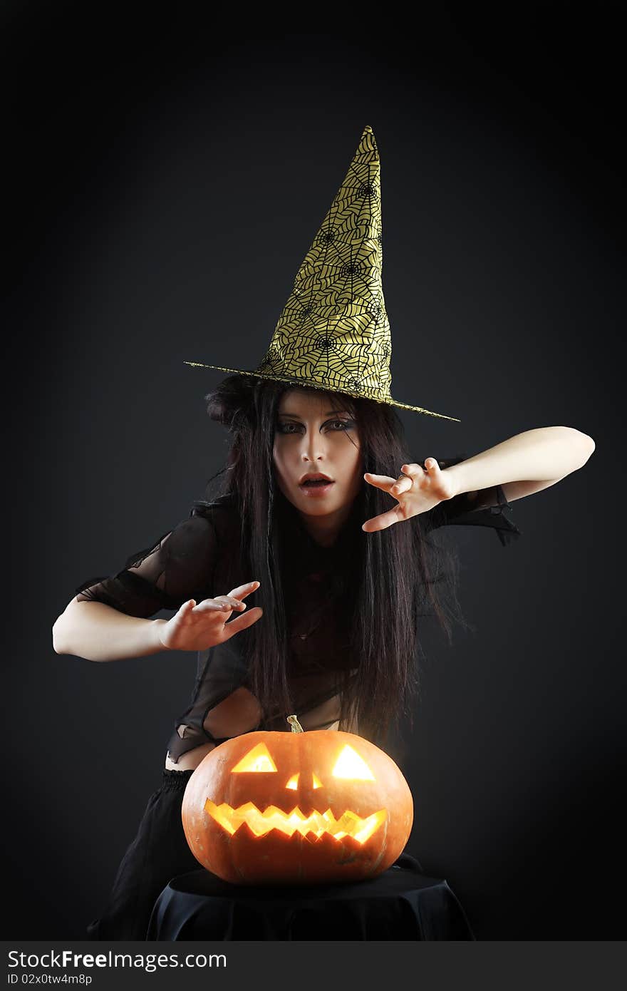 Halloween witch with a broom and carved pumpkin over black background.