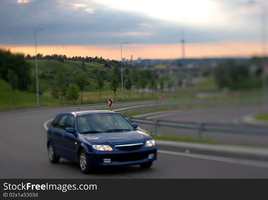 Dark blue car on the turn in evening light. Dark blue car on the turn in evening light.