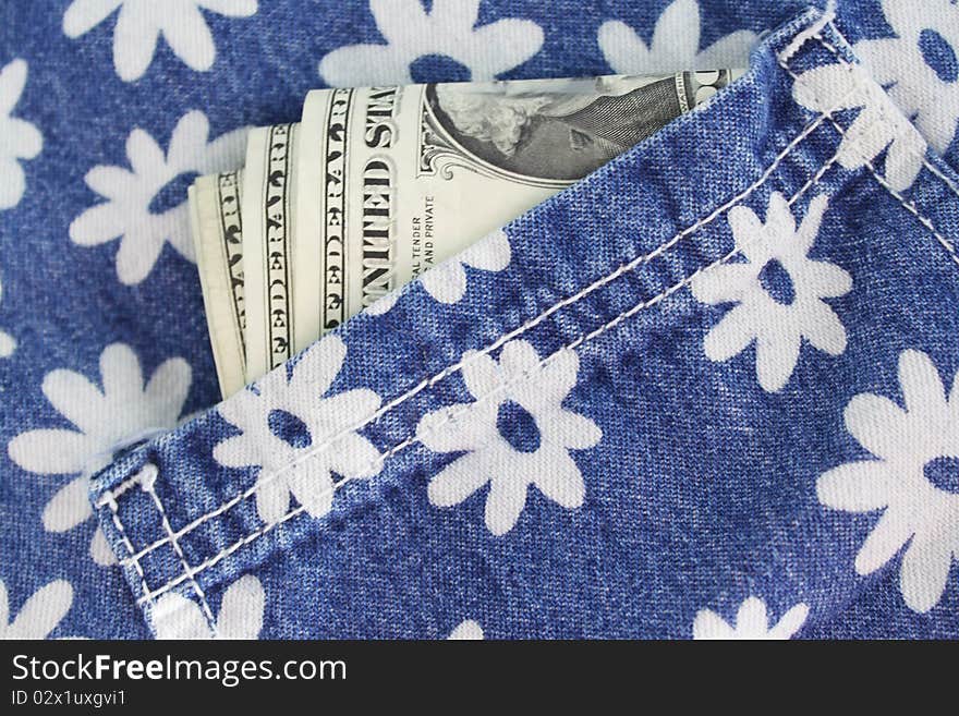 Some bills sticking out of the pocket of jeans with a flower pattern. Some bills sticking out of the pocket of jeans with a flower pattern.