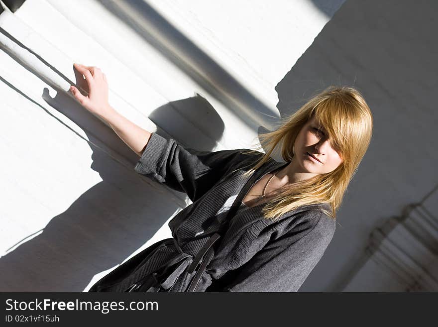 Teenager is standing in front of white wall of brick and looking. Teenager is standing in front of white wall of brick and looking.