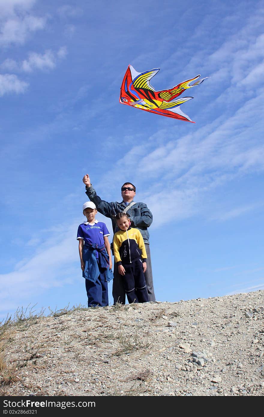 The father with children and with a kite in the blue sky