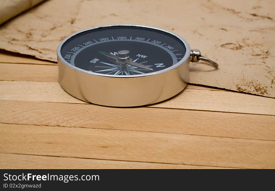 Compass with an old paper on a wooden background