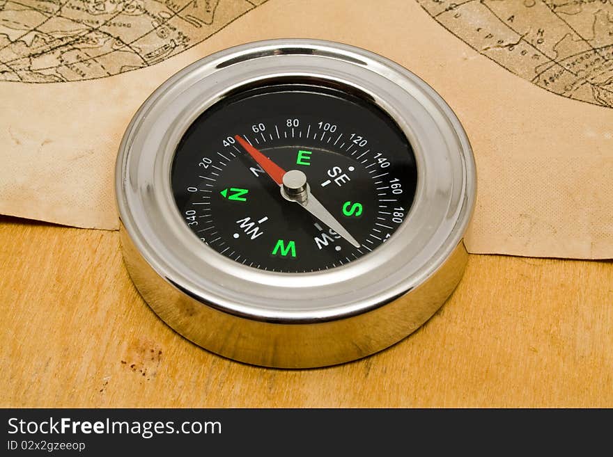 Compass with an old paper on a wooden background