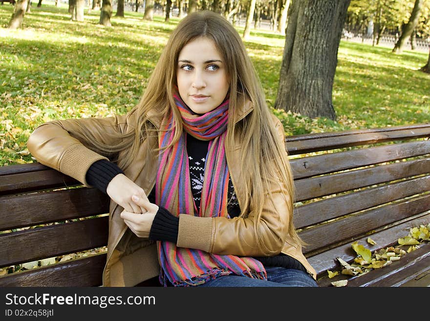 Horizontal portrait of a beautiful young woman sitting on a bench in the park around a lot of yellow, red green leaves. Horizontal portrait of a beautiful young woman sitting on a bench in the park around a lot of yellow, red green leaves.