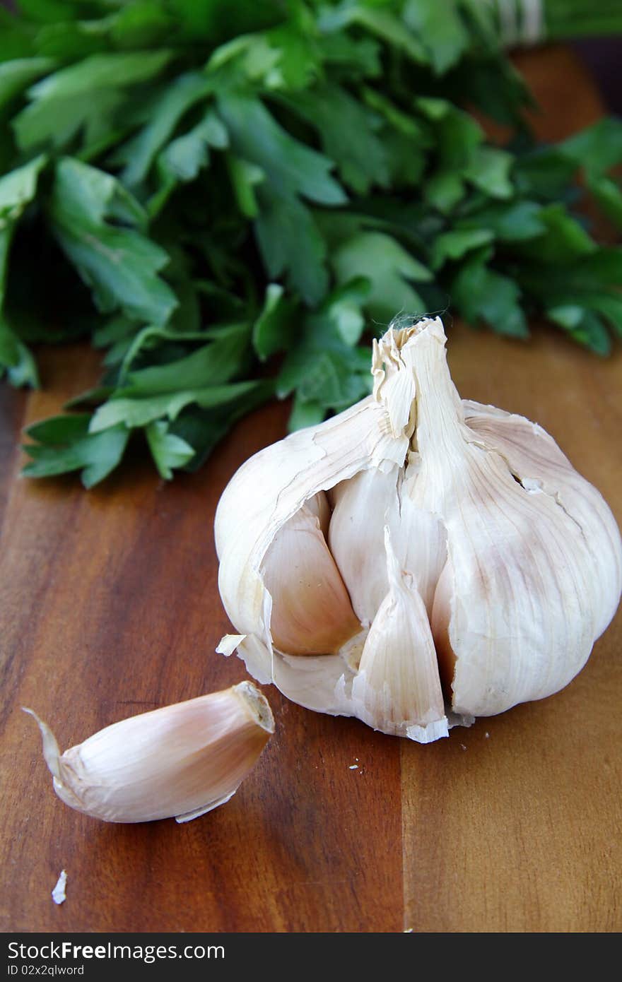 Garlic on a wooden board with green in the background