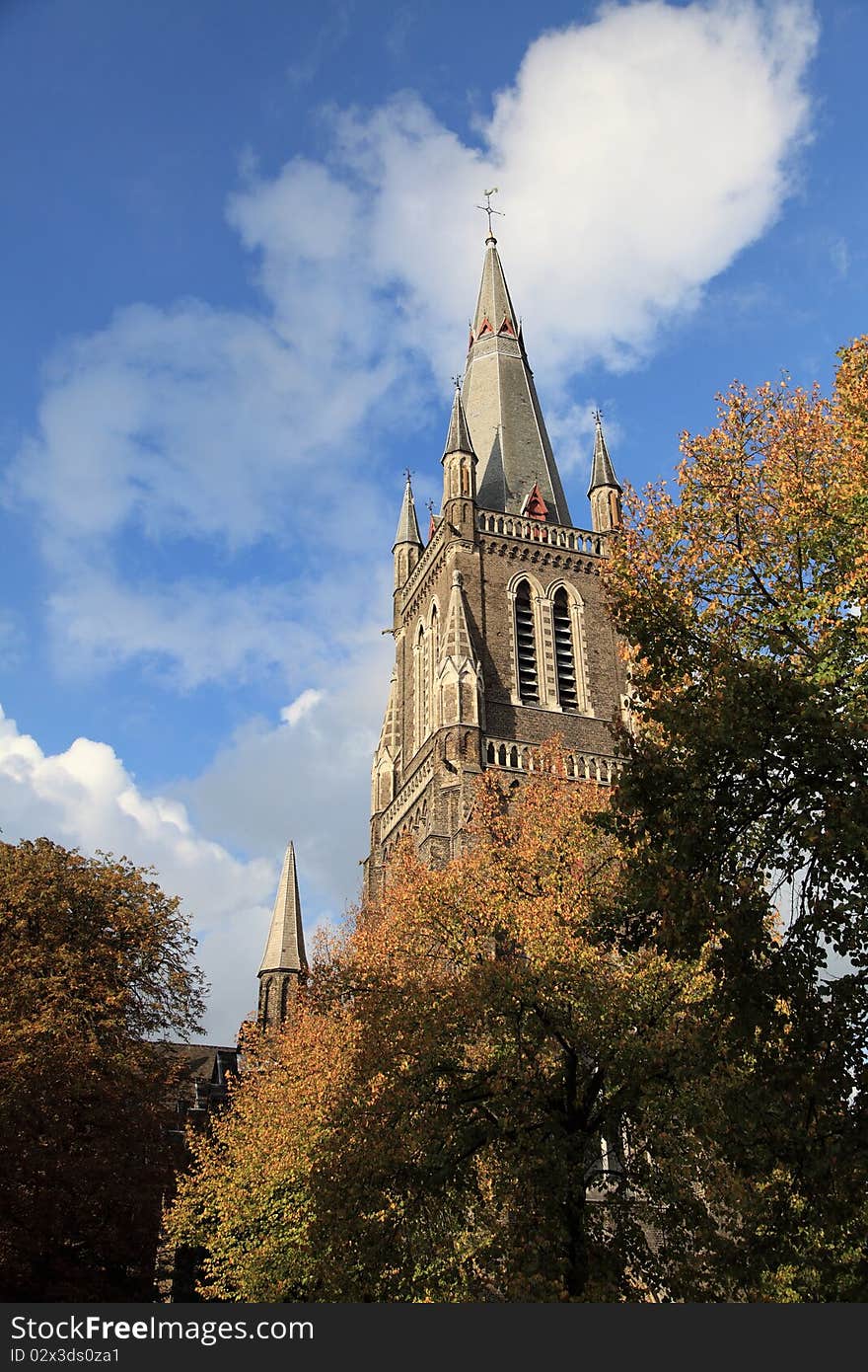 A church in Bruges, under clear sky and surrounded by trees