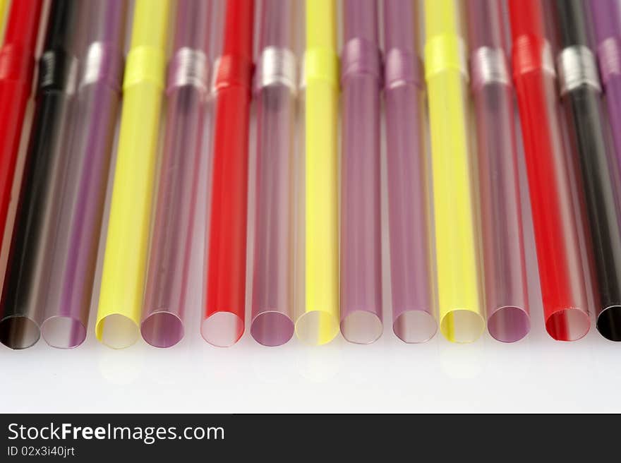 Straws of various colours on a white background