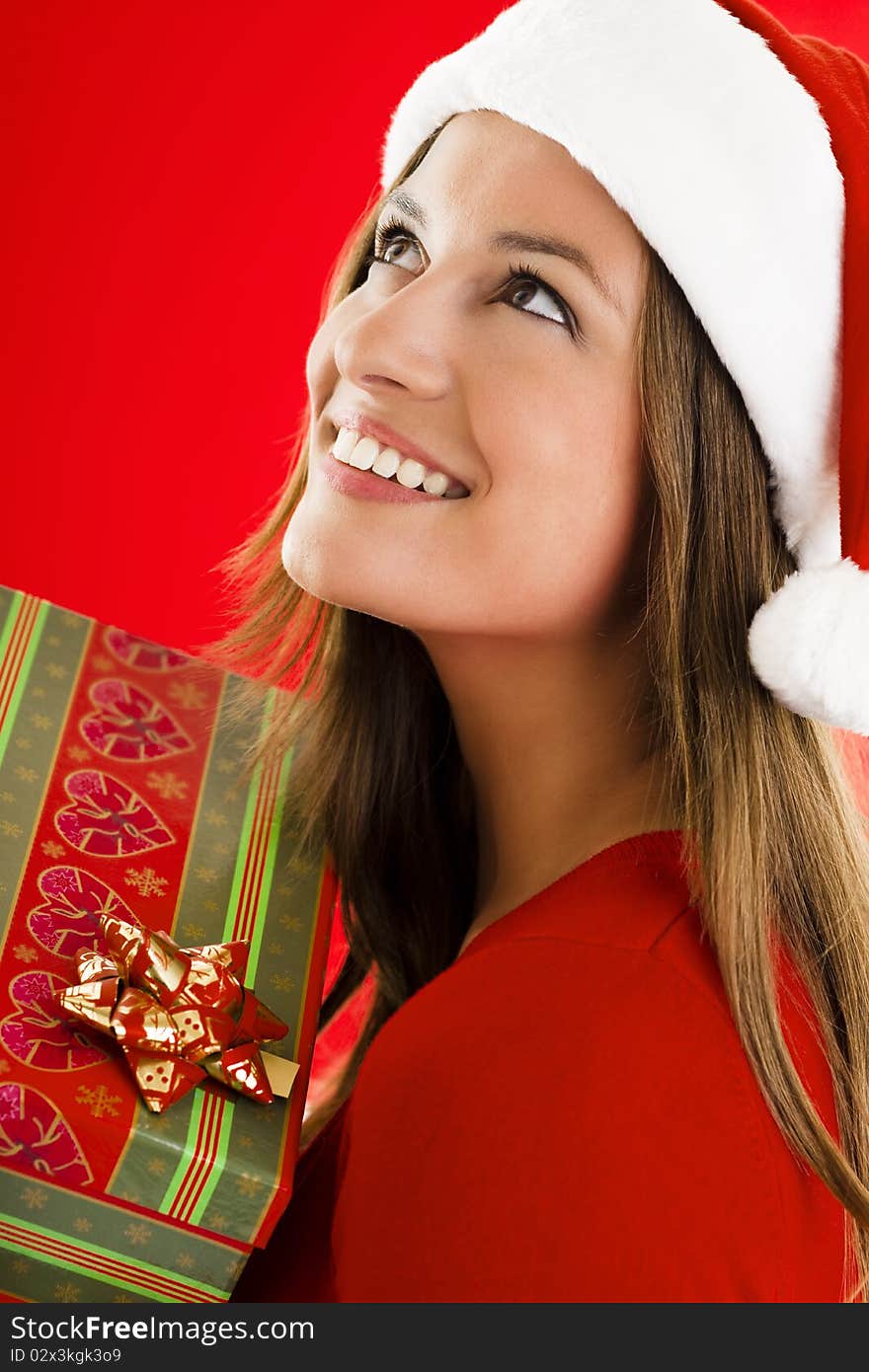 Portrait of a smiling and dreaming Santa Girl with present