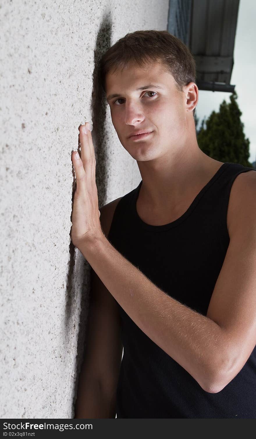 Young teenage boy leaning against a wall in anurban setting. Young teenage boy leaning against a wall in anurban setting.