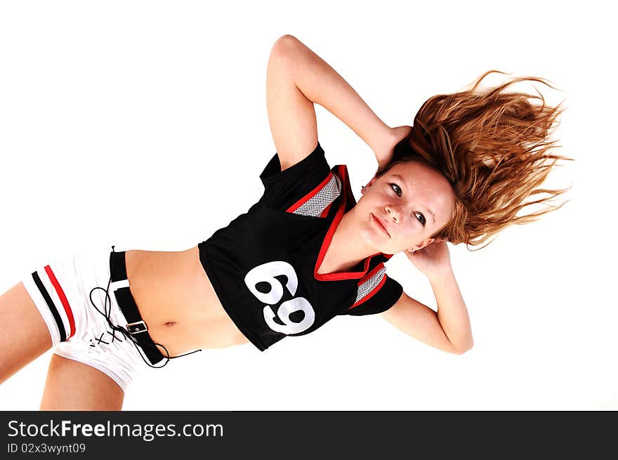 A young teenage soccer girl lying on the floor in her uniform, hands behind her head, for a portrait in the studio, over white background. A young teenage soccer girl lying on the floor in her uniform, hands behind her head, for a portrait in the studio, over white background.