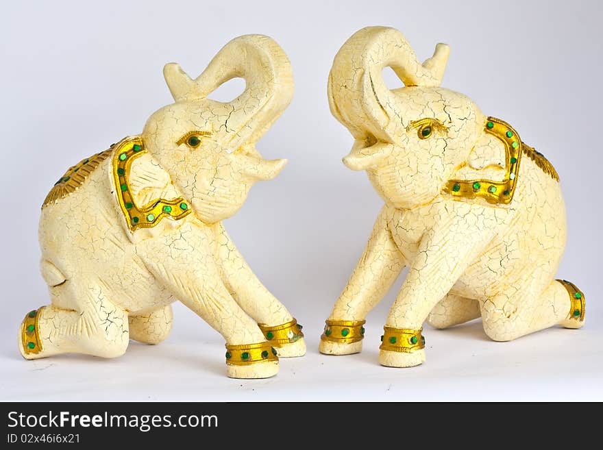 White elephants engraving from wood with gold dressed kneeing on the floor and raise his nose on the top.