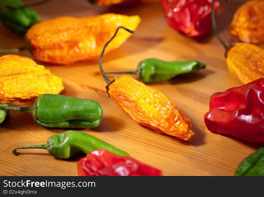 Collection of multicolored hot chili peppers on a wooden table. Selective focus. Shallow depth of field. Collection of multicolored hot chili peppers on a wooden table. Selective focus. Shallow depth of field.