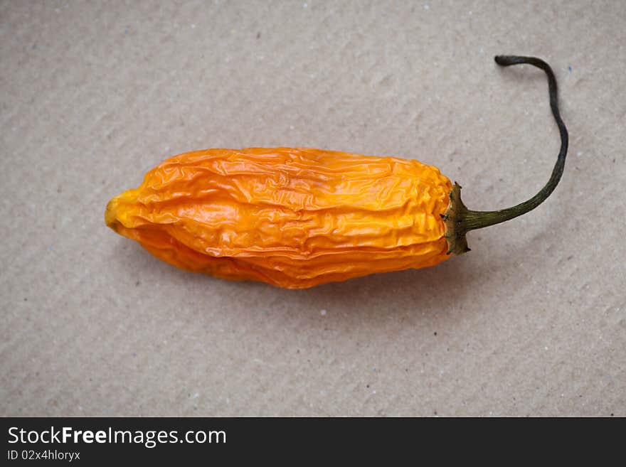 Hot orange chili peppers on a cardboard background. Hot orange chili peppers on a cardboard background