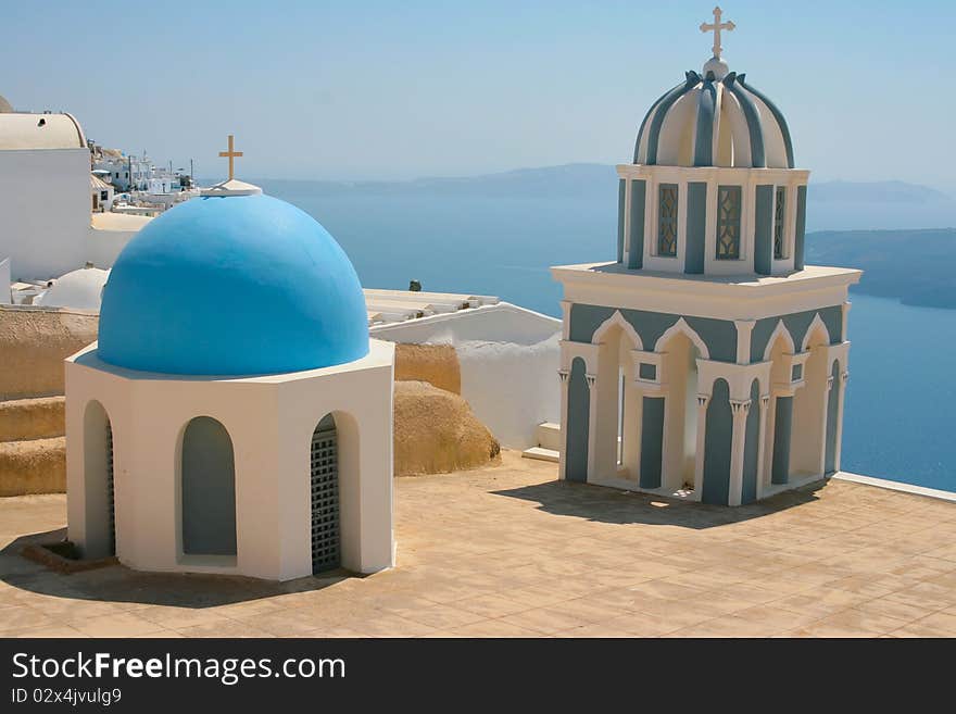 Two classic small beautiful churches in Fira on island of Santorini, Greece. Caldera view on a background. Two classic small beautiful churches in Fira on island of Santorini, Greece. Caldera view on a background.