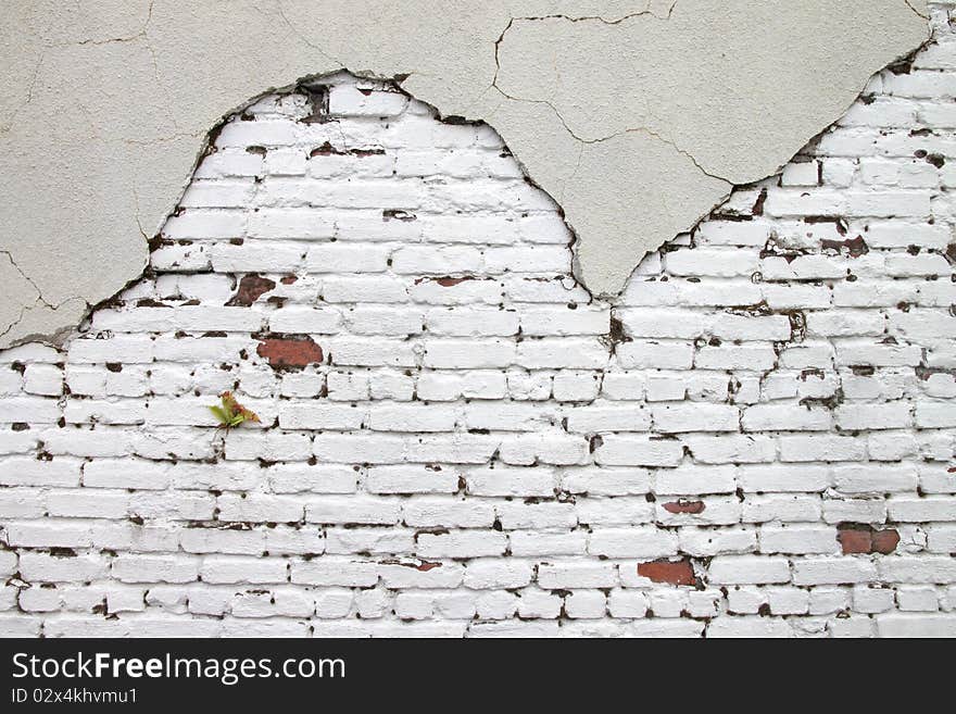 Red brick shows through a cracked stucco exterior. Red brick shows through a cracked stucco exterior.