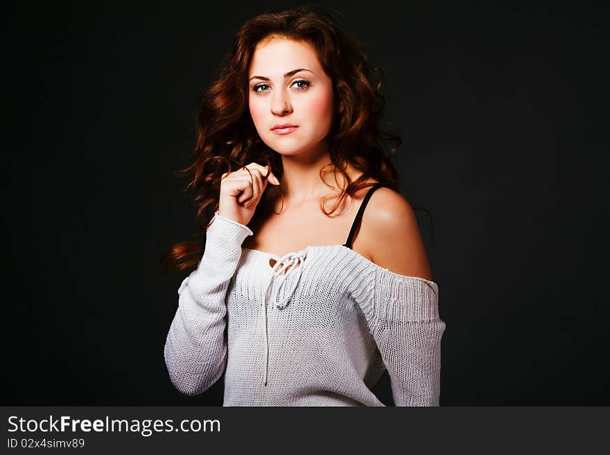 Portrait of a attractive young brunette in sweater on gray background