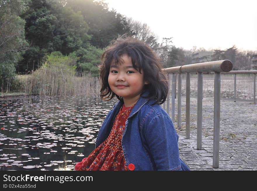 The portrait of a Malay girl that Smiles while sitting by a lake in Spring Season. The portrait of a Malay girl that Smiles while sitting by a lake in Spring Season