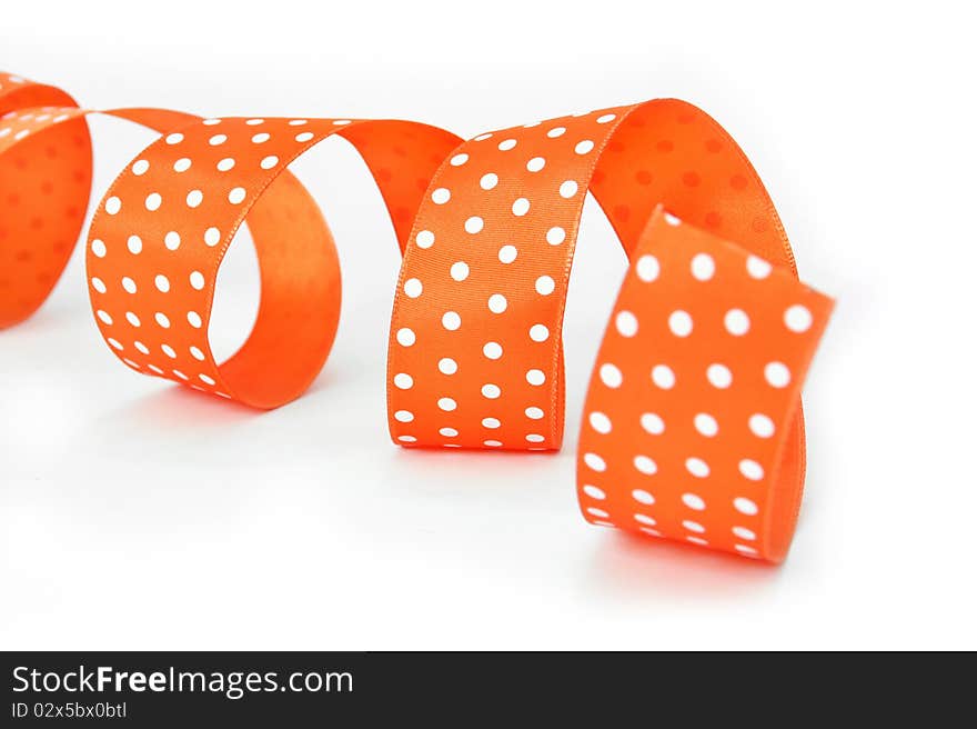 An orange fabric ribbon with white polkadots, curled and with a shallow DOF. An orange fabric ribbon with white polkadots, curled and with a shallow DOF