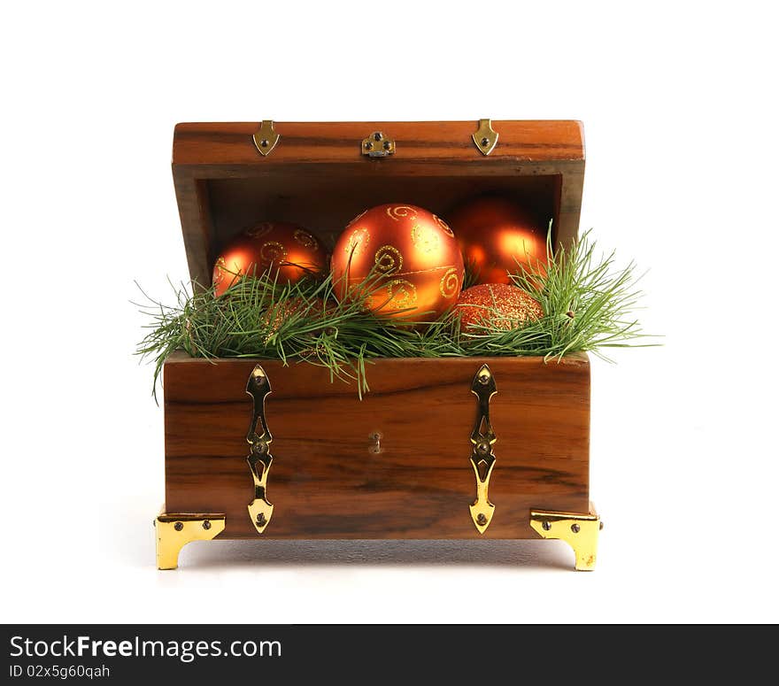 An ancient brown treasure chest full of spruce needles and Christmas balls. The image is isolated on a white background. An ancient brown treasure chest full of spruce needles and Christmas balls. The image is isolated on a white background.