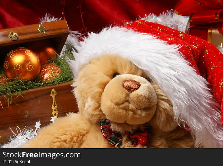 Christmas image of a cute teddy bear in a red Christmas hat. Evening balls and spruce needles are added to the background. Christmas image of a cute teddy bear in a red Christmas hat. Evening balls and spruce needles are added to the background.