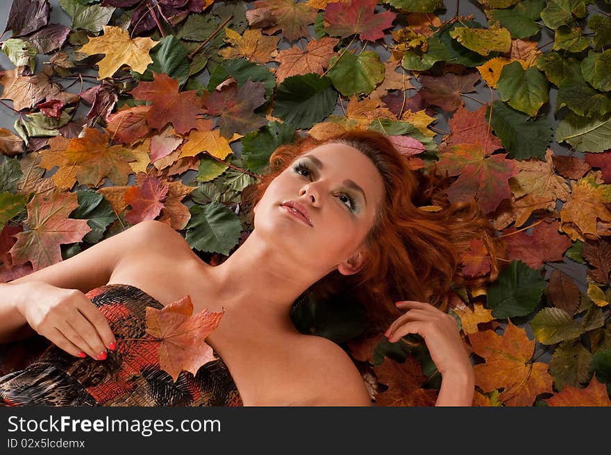 Portrait of a young and beautiful woman lying on a background with fallen autumn leaves. Portrait of a young and beautiful woman lying on a background with fallen autumn leaves.