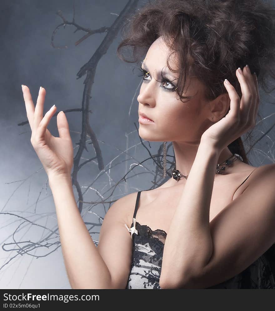 Fashion portrait of a young and attractive brunette in a dark dress. The image is taken on a mystique and foggy background. Fashion portrait of a young and attractive brunette in a dark dress. The image is taken on a mystique and foggy background.