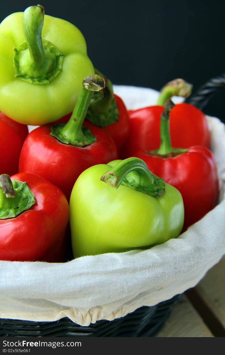 A lot of red and green peppers on a wooden table