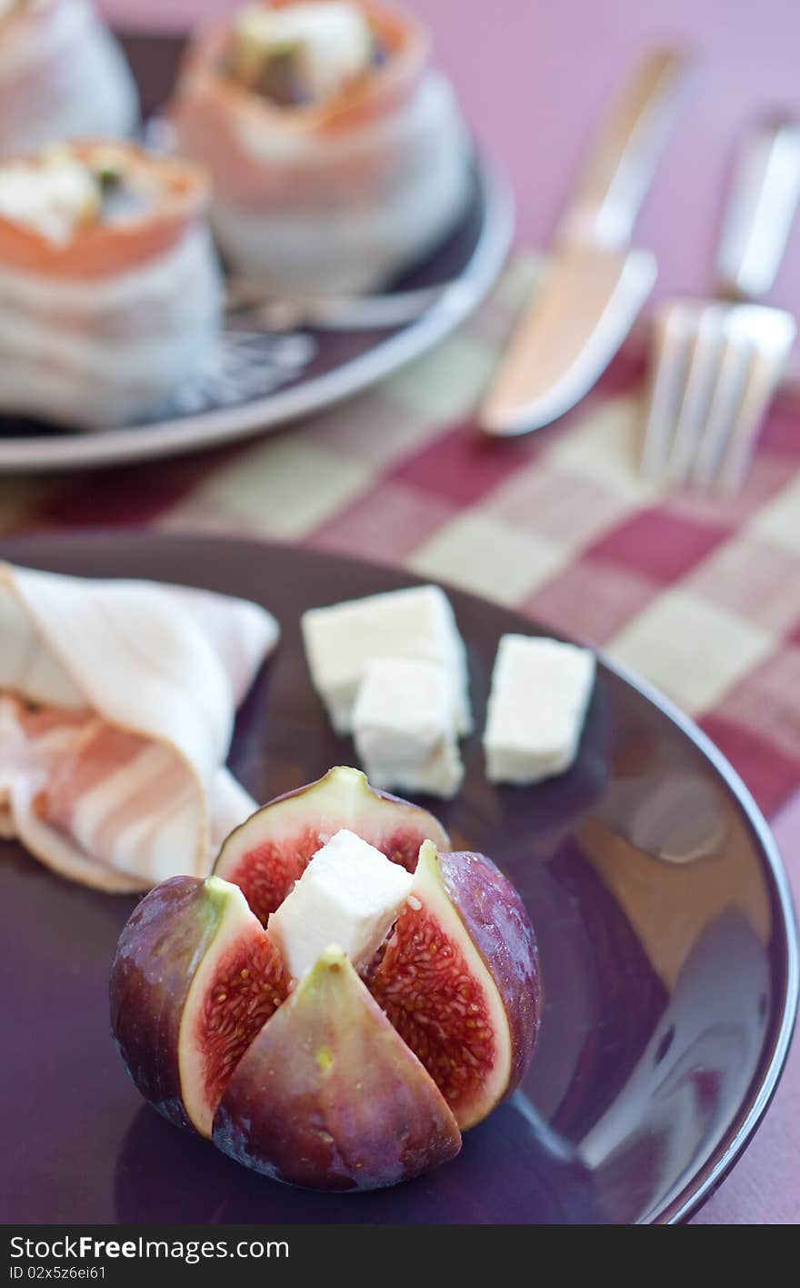 Fresh diced figs on the colorful plate with feta cheese and bacon on the background. Fresh diced figs on the colorful plate with feta cheese and bacon on the background